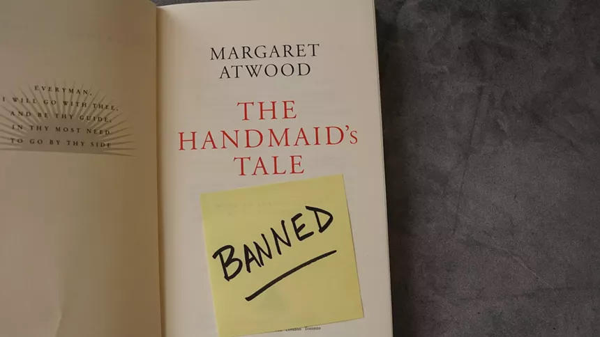 sticky note saying "banned" on the title page inside a copy of "The Handmaid's Tale" by Margaret Atwood. The book has landed on many school and library banned book lists